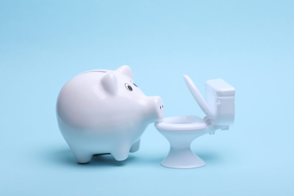 Tirelire blanche en forme de cochon en céramique avec toilettes sur fond bleu.